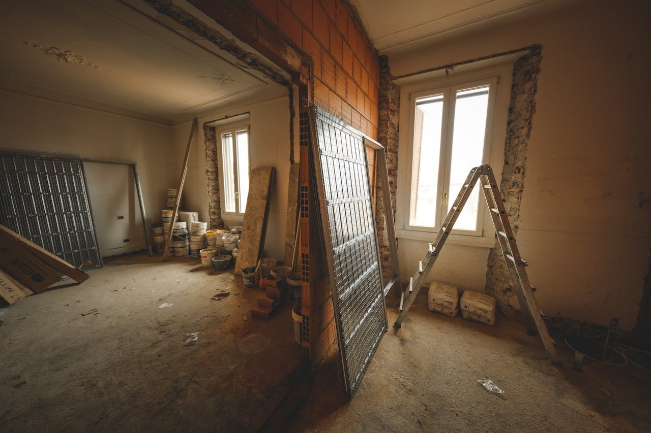 about-us Interior view of a room under renovation with construction materials and a ladder.